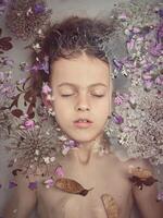 A young girl is floating in a bathtub with flowers photo