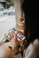 A woman is using her phone while sitting at a table photo