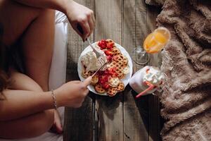 A person eating a waffle with strawberries and whipped cream photo