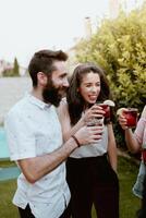Three friends toasting with drinks in front of a pool photo