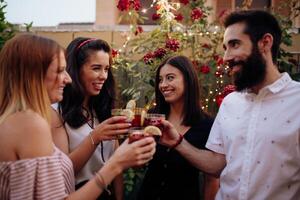 Four friends toasting with drinks in front of a garden photo