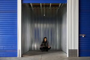A woman sitting in the middle of a storage unit photo