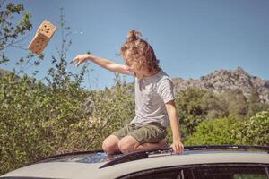 A young boy sitting on top of a car with a box photo
