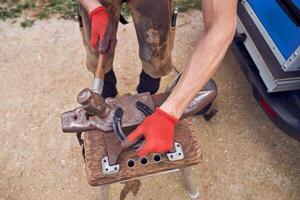 A man is using an anvil to hammer a piece of wood photo
