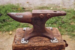 A rusty anvil sitting on a wooden block photo