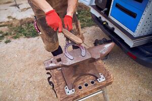A man is using a hammer to make a horseshoe photo