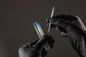 concept dry needling method. Close-up of black-gloved hands holding sterile acupuncture needles in protective tubes, symbolizing alternative medicine, precision, and healthcare. photo