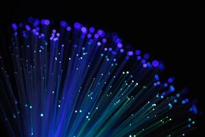 Glowing fiber optic cables with vibrant blue and purple bokeh lights on a dark background, representing fast internet, data transfer, and technology photo