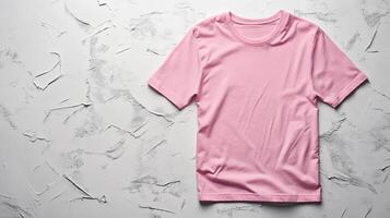 Bright pink t shirt displayed on textured white surface from a top view highlighting its color and fabric quality photo