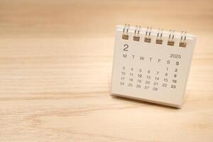 Desk Calendar for FEBRUARY 2025 background. Calendar concept with 2025 FEB calendar on wooden background. Copy Space for text. photo