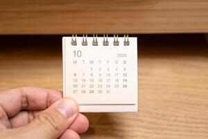 Desk Calendar for OCTOBER 2025 background. Calendar concept with 2025 OCT calendar on wooden background. photo