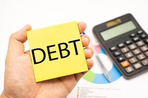 DEBT text on Sticky note with Calculator. Economic crisis risk and problem concept. Financial debt decrease, revenue management concept. photo
