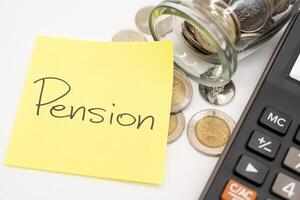 PENSION text on sticky note. Thai Baht Coins spilled out of jar glass isolated on white background. photo
