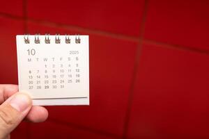 Desk Calendar for OCTOBER 2025 background. Calendar concept with 2025 OCT calendar on red background. photo