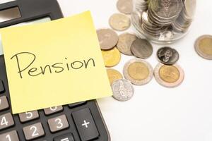 PENSION text on sticky note with Calculator. Thai Baht Coins spilled out of jar glass isolated on white background, saving for future. Copy Space for text. photo