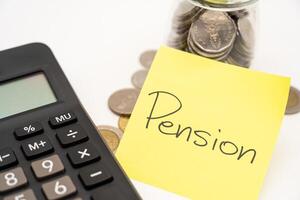 PENSION text on sticky note with Calculator. Thai Baht Coins spilled out of jar glass isolated on white background, saving for future. photo