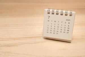 Desk Calendar for JULY 2025 background. Calendar concept with 2025 JUL calendar on wooden background. Copy Space for text. photo