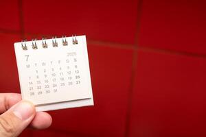 Desk Calendar for JULY 2025 background. Calendar concept with 2025 JUL calendar on red background. photo