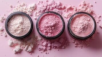 Colorful makeup powders scattered on a pink surface with three open containers showcasing the different shades and textures photo