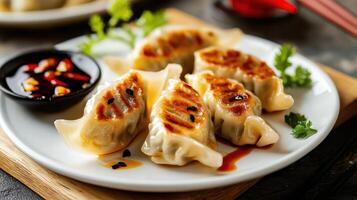 Dumplings served on a plate with dipping sauce and garnished with herbs in a cozy dining setting during dinner time photo