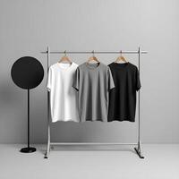 Three t - shirts hanging on a rack with a black and white one photo