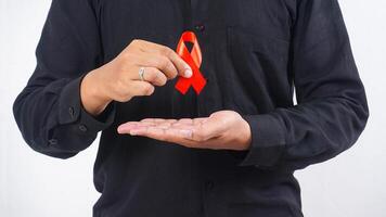 Man holding red ribbon awareness on his chest isolated on white background photo