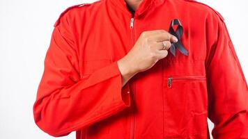 Hand of man holding black ribbon in front of his chest as symbol of mourning and melanoma cancer awareness isolated on white background photo