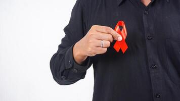 Man holding red ribbon in front of his chest as symbol of awareness isolated on white background photo