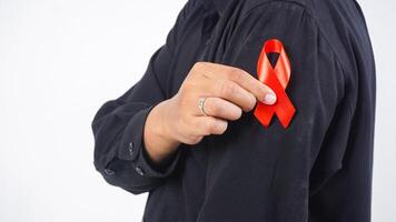 Man holding red awareness ribbon in front of his chest isolated on white background photo