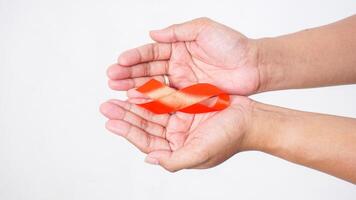 Hands showing red ribbon for awareness symbol on palm on white background photo