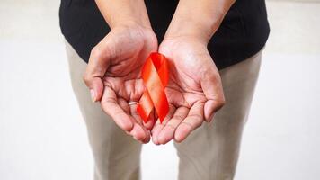 Red ribbon awareness in man hands isolated on white background photo