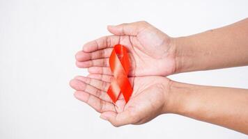 Hands showing red awareness ribbon on palm on white background photo