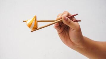 Chopsticks holding raw fish dumpling ball stuffed with cheese isolated on white background photo