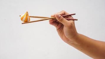 Chopsticks holding fish dumpling ball stuffed with cheese isolated on white background photo