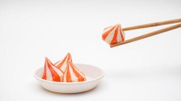 Fish dumpling balls stuffed with chicken meat on small bowl and picked up using chopsticks isolated on white background photo
