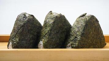 Three Japanese rice ball wrapped in nori dried seaweed or onigiri on wooden coaster isolated on white background photo