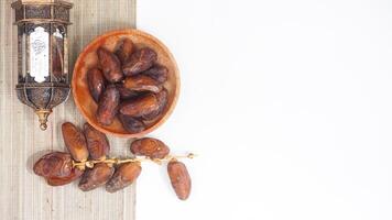 Dried Dates Fruit on Wooden Plate for Ramadan Nutritious Snack Isolated on White Background photo