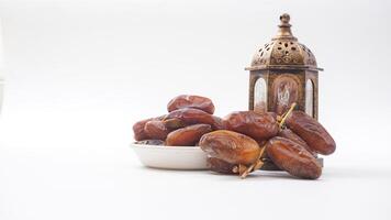 Sweet Dates Fruit on Bowl for Ramadan Iftar with Islamic Lantern Isolated on White Background photo