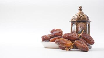 Delicious Dates Fruit on Bowl for Ramadan Iftar with Islamic Lantern Isolated on White Background photo