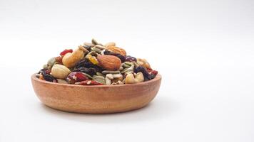 Nutritious blend of nuts seeds and dried fruits on wooden plate isolated on white background photo