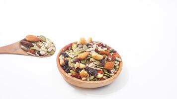 Nutritious blend of nuts seeds and dried fruits on wooden plate and spoon isolated on white background photo
