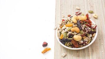 Premium mixed nuts seeds and dried fruits on bowl isolated on white background photo