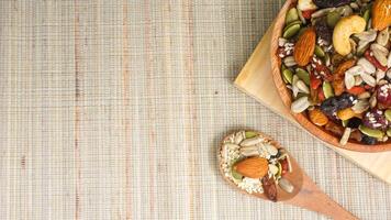 Healthy mix of nuts seeds and dried fruits on wooden plate and spoon isolated on wooden background photo