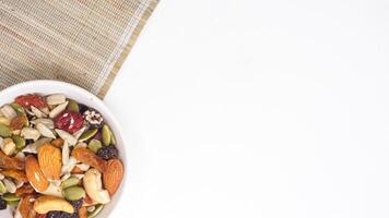 Nutritious blend of nuts seeds and dried fruits on bowl isolated on white background photo