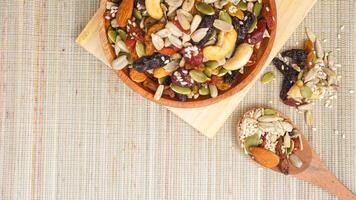 Nutritious blend of nuts seeds and dried fruits on wooden plate and spoon isolated on wooden background photo