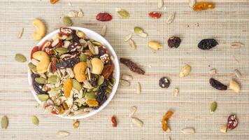 High energy nuts seeds and dried fruits mix on bowl isolated on wooden background photo