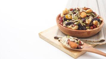Perfect snack mix of nuts seeds and dried fruits on wooden plate and spoon isolated on white background photo