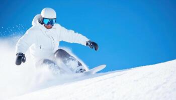 Snowboarder carving downhill on fresh snow under clear blue sky, showcasing skill and excitement in winter sports photo