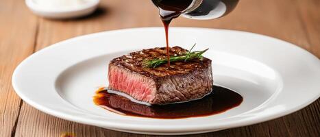 chef pouring rich brown sauce over medium rare steak, garnished with herbs, creates mouthwatering presentation. dish is served on white plate, highlighting juicy texture and vibrant colors photo