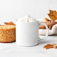 white ceramic mug filled with whipped cream, surrounded by cake, cookies, and autumn leaves, creating cozy atmosphere photo